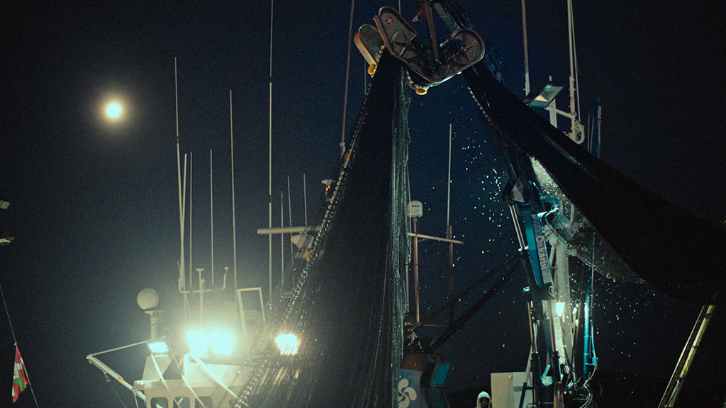 Pescadores trabajando bajo la oscuridad mientras izan las redes, en un homenaje visual al oficio y la pesca. Agradecidos